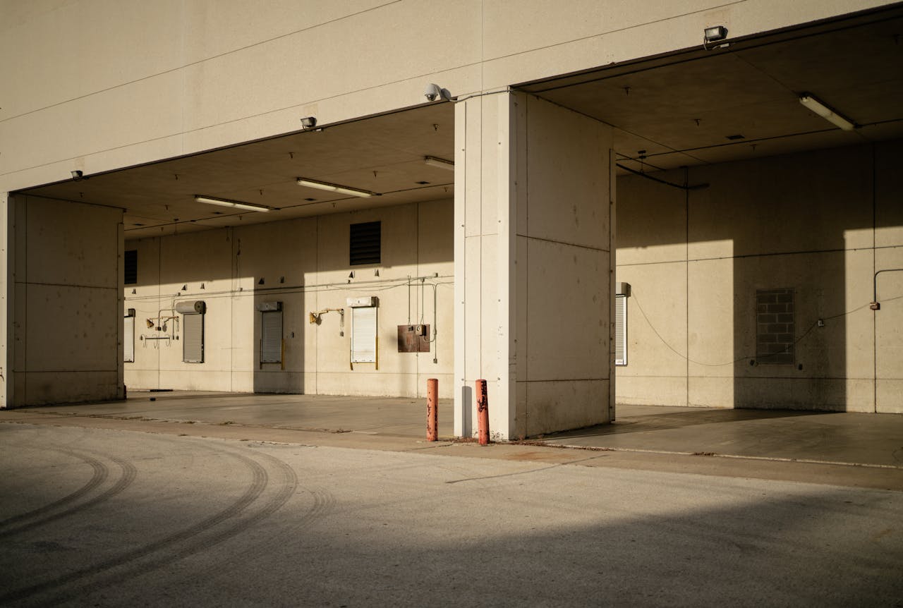 Empty industrial loading dock with sunlight casting shadows on walls.